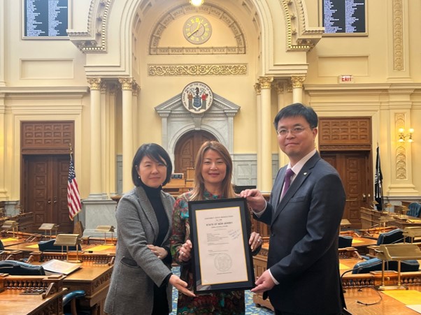 Photo: Director Shim Hwa-seop (right) of the US branch of the Korea Agro-Fisheries & Food Trade Corporation and Deputy Director Jang Ji-hee (left) receive a copy of the bill from Assemblywoman Ellen Park (middle) to commemorate the bill's passage.