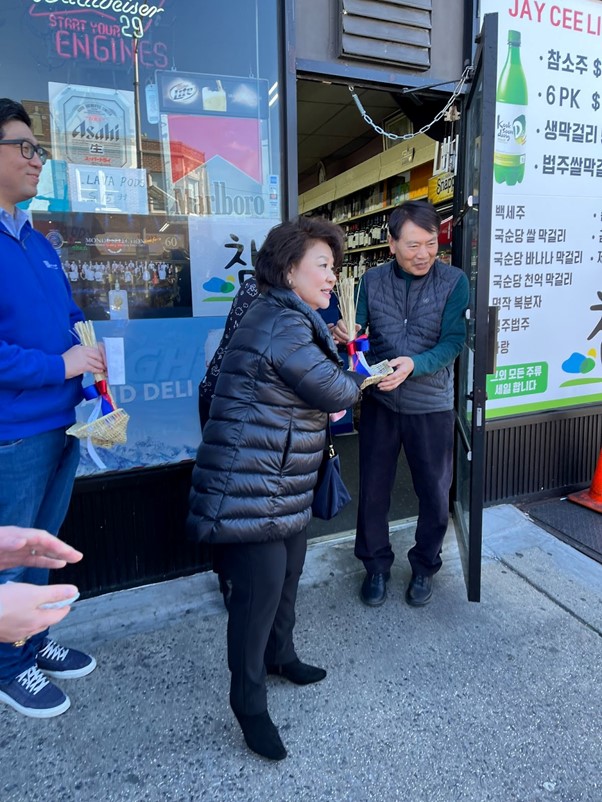 Photo: President Cha Yeong-ja of the Korean-American Senior Citizen's Association offering a bokjori to a Korean store owner.