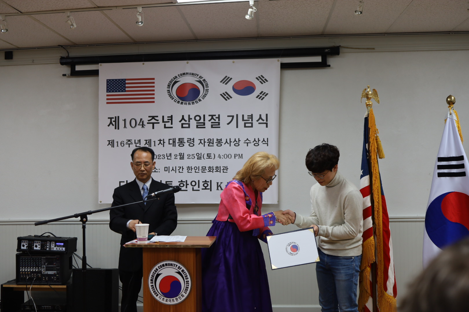 Lee Min-hui (16) receives a volunteer service award from the president of the Korean American Community of Metro Detroit